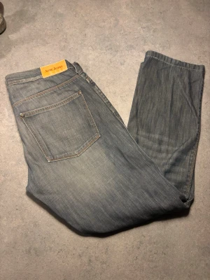 Ljusblå raka jeans från Acne Jeans - Säljer ett par ljusblå jeans från Acne Jeans med klassisk rak passform och diskret slitning. Jeansen har fem fickor, gylf med dragkedja och knapp samt en snygg läderpatch med logga bak i midjan. Jeansen Är små i storleken!