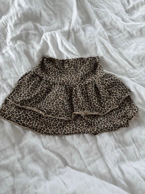 Leopardmönstrad volangkjol - Snygg kort kjol med leopardmönster och dubbla volanger. Kan även användas som topp!😍💓 Kjolen har en beige bas med leopardmönster🐆 Perfekt för dig som vill sticka ut med en trendig och lekfull stil. Materialet känns mjukt och följsamt💛💛