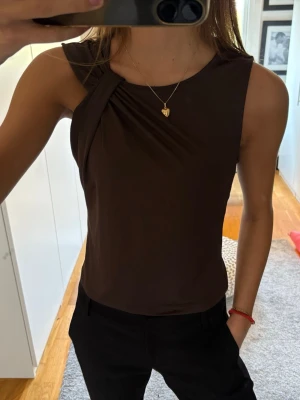 Brun topp - Brun topp med detaljer vid ena axeln 