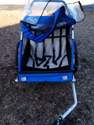 Blå cykelvagn för barn - Säljer en blå cykelvagn med plats för två barn. Vagnen har genomskinligt regnskydd, säkerhetsbälten och stora hjul med reflexer. Perfekt för cykelturer med barnen och enkel att koppla på cykeln. Tillverkad i slitstark textil och metall.Övergripande mått: 130L x 76W x 88H cm, Inredning: 74L x 60W x 56H cm, Sits: 59L x 24W x 45H cm Rekommenderas för personer från 18 månader och uppåt. Lastkapacitet: 40 kg.