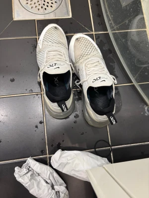 Nike Air Max 270 vita sneakers - Nike Air Max 270 sneakers i vitt med mesh-överdel och stora synliga Air Max-sulor. Använda, totalt 3 hål. Två framme och 1 i luftbubblan 