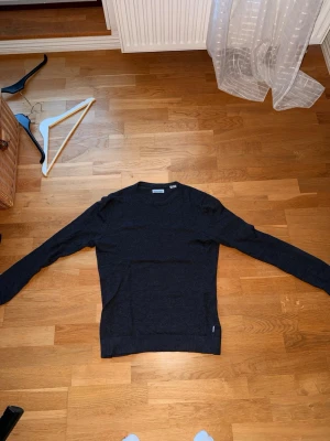 Mörkgrå tröja från Jack & Jones - En stilren mörkgrå tröja från Jack & Jones med rund halsringning och långa ärmar. Tröjan har en enkel och clean design som passar perfekt till jeans eller chinos. Materialet känns mjukt och bekvämt mot huden. Nypris 449