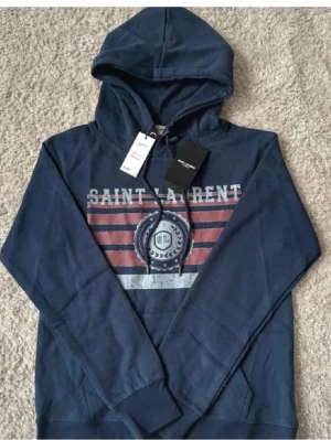 Mörkblå saint Laurent hoodie  - Säljer en riktigt fet sl hoodie skick 9/10✨, är 175 och den sitter perfa i längden🙌🏻 pris är ej hugget i sten 🪨