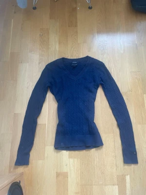 Mörkblå stickad tröja med V-ringning - Säljer en mörkblå stickad tröja med V-ringning och kabelstickat mönster. 