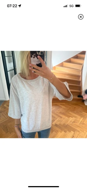 Ljusgrå loose topp med trekvartsärm - En enkel och stilren ljusgrå topp med loose passform och trekvartsärmar. Toppen har rund halsringning och är tillverkad i mjukt bomullsmaterial. LÅNADE BILDER