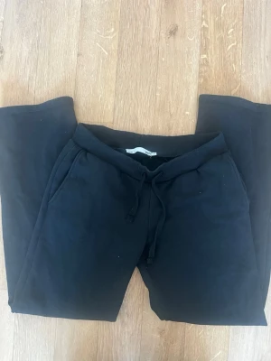 Svarta mjukisbyxor low waist från 157 - Svarta mjukisbyxor low waist från 157 med dragsko i midjan och ribbade muddar. Byxorna har två sidofickor och är gjorda i ett mjukt, bekvämt material som passar perfekt för chill dagar. Klassisk och enkel design som funkar till det mesta.