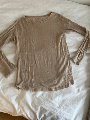 Beige långärmad topp i bomull - En enkel och stilren beige långärmad topp med rund halsringning. Tillverkad i mjuk bomull som känns skön mot huden. Perfekt att matcha med jeans eller kjol för en avslappnad look.