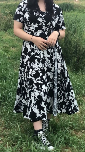 Svartvit omlottklänning - Säljer en svartvit omlottklänning med blommigt mönster. Klänningen har v-ringning, knyt i midjan och korta ärmar. Tyget är mjukt och stretchigt. Perfekt för dig som gillar en flowy och bekväm stil. Kläningen har inga skador och använd bara ett par gånger.