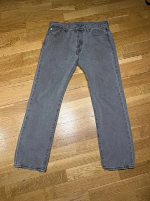 Grå raka jeans från Levi's - Säljer ett par grå jeans från Levi's med klassisk rak passform och fem fickor. Jeansen har en diskret tvätt och är tillverkade i slitstark denim. Perfekta för dig som gillar en clean och tidlös stil.
