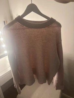 Ljusrosa stickad tröja Gina Tricot - Supersöt ljusrosa stickad tröja från Gina Tricot med bred ribbad krage, muddar och nederkant. Tröjan har en avslappnad passform och är perfekt för lager på lager. Materialet känns mjukt och lätt, vilket gör den skön att bära hela dagen.