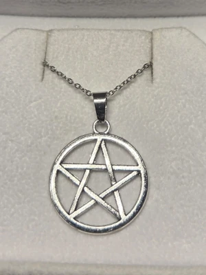Halsband med pentagram hänge  - Stilrent halsband i silverfärgat rostfritt stål med ett pentagram hänge. Kedjan har ovala länkar och passar perfekt för en minimalistisk look. Perfekt accessoar för att lyfta din outfit med en diskret detalj. Kedjan är 45 cm.