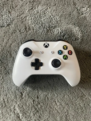 Vit Xbox One handkontroll - (OBS UTAN BATTERI:349)Snygg vit Xbox One handkontroll med svart D-pad och svarta detaljer. Klassisk ergonomisk form med två analoga spakar, styrkors och färgade knappar (A, B, X, Y). Tillverkad i plast och passar perfekt för gaming på Xbox eller PC. 