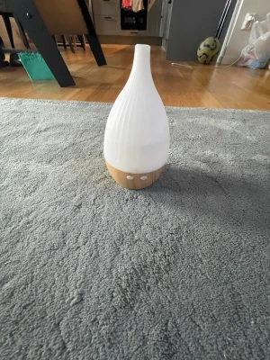 Vit aromadiffuser med trädetalj - Snygg aromadiffuser i droppformad design med vit ovandel och botten i träimitation. Perfekt för att sprida doft och skapa en avslappnad stämning hemma. Enkel att använda med två knappar på framsidan.