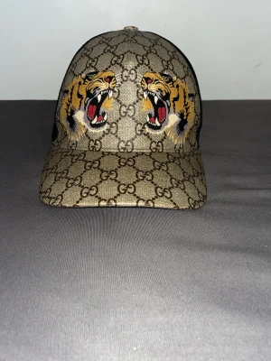 Gucci keps tiger  - Snygg keps från Gucci med klassiskt GG-mönster i beige och brunt.  Tiger gucci keps strl M den är ny inga problem eller några skador som ni ser den är äkta och ny modell chippen följer med kepsen också pris kan alltid diskuteras och tar byten mot andra gucci kepsar också om de är äkta 