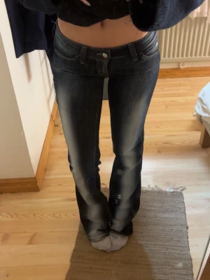 Mörkblå bootcut jeans från Cheap Monday - Säljer ett par mörkblå bootcut jeans från Cheap Monday med snygga slitningar och kontrastsömmar. Jeansen har låg midja, klassiska fem fickor och en stor vit logolapp bak. Perfekta för en avslappnad och trendig look. Storlek 26/34 Och jag är 165 som referens, dom är lite långa för mig