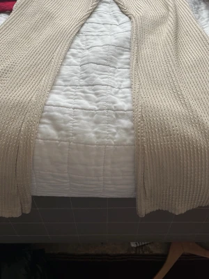 Beige ribbat loungewear-set - Mysigt loungewear-set i beige ribbat material. Setet består av ett par vida byxor och en topp med kort ärm och volangdetaljer vid axlarna. Perfekt för chill dagar hemma. Materialet är mjukt och stretchigt för extra komfort.