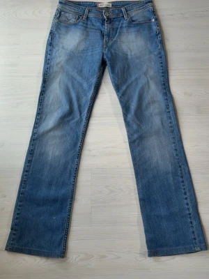 Levi's 627 - Ett par klassiska blå bootcut jeans från Levi's med fem fickor och lätta slitningar framtill och baktill. Jeansen har en snygg tvätt och Levi's ikoniska röda etikett på bakfickan. Passar en avslappnad look.