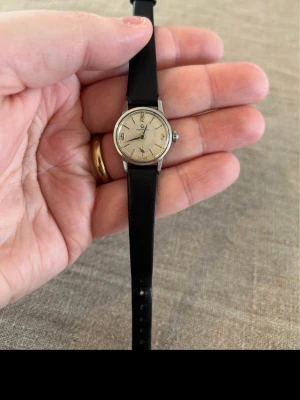 1960 Certina Mekanisk 18mm Går! - Säljer en otroligt fin 60-tals (62/63) klocka från schweiziska Certina i grymt bra skick. Finns tunna repor på glaset som knappt syns. Säljes i befintligt skick enligt bilder. Fungerar utmärkt och går, armband i svart läder, datumvisare, schweiziskt manuellt urverk, vattentät osv. Fås i söt liten presentask.  Begagnat pris: 700 SEK Mitt pris: 589 SEK  Skickas alltid snabbt och spårbart (ofta samma dag) eller hämtas i Glumslöv.  Hör av dig vid frågor och se gärna mina andra annonser också!