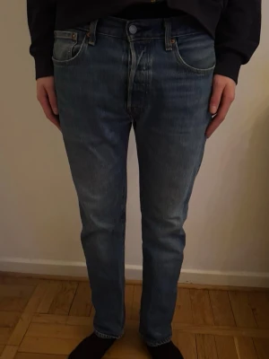 Blå raka jeans från Levi's - Modellen är 187cm Säljer ett par klassiska blå jeans från Levi's med rak passform och fem fickor. Jeansen har en snygg tvättad look och den ikoniska röda Levi's-lappen på bakfickan. Tillverkade i slitstark denim, perfekta för en avslappnad stil.
