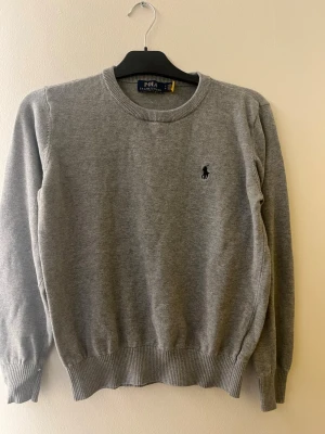 Polo Ralph Lauren stickad tröja grå – storlek S – mycket fint skick - Grå stickad tröja från Polo Ralph Lauren.  • Storlek: S   • Färg: Grå   • Klassisk modell med broderad logga på bröstet   • Mycket bra skick  Stilren och lätt att matcha med jeans eller chinos. Säljs eftersom den inte används längre.  Pris kan diskuteras. 
