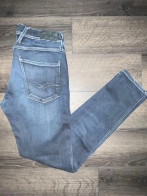 Replay anbass jeans 31/32 - Snygga Replay Anbass Jeans i mörkblå tvätt med coola slitningar och kontrastsömmar. Modellen har klassiska fem fickor, raka ben och normal passform. Materialet är mjukt jeans-tyg med stretch för extra komfort. Midja 38cm, Längd 100cm. JAG SKICKAR INGA FLER BILDER NÄR JAG BÄR JEANSEN:)