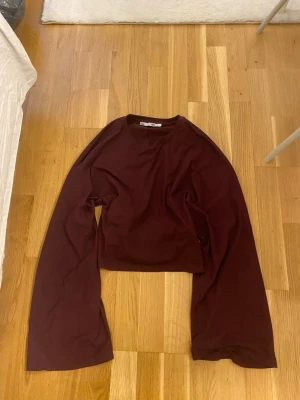 Vinröd croppad topp med knyt - vinröd croppad topp med långa ärmar och snygg knytning i ryggen. Mjukt och stretchigt, vilket gör den bekväm att bära.