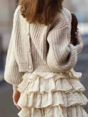 Beige unik Tikka knit med pärlknappar från Custommade dyr i inköp!  - Supersöt beige ribbstickad kofta med dekorativa pärlknappar framtill. Koftan har en croppad passform, ballongärmar och bred ribbad mudd vid ärmslut och hals. Perfekt att styla över klänning eller till jeans för en trendig look.