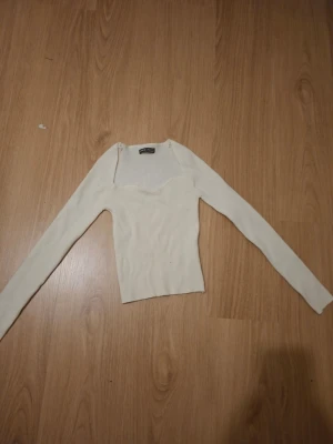 Ljus ribbad långärmad topp - Trendig ljus ribbad topp med lång ärm och snygg v-ringad halsringning. Figurnära passform och stretchigt material som passar perfekt till jeans eller kjol. Enkel men stilren design.