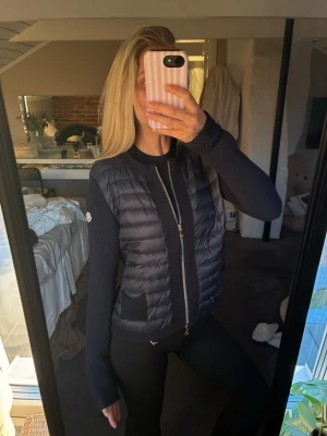 Mörkblå cardiganjacka från Moncler - Snygg mörkblå cardiganjacka från Moncler med quiltad front och stickade ärmar. Jackan har dragkedja framtill, två fickor och Moncler-logga på ärmen. Den finns inte kvar att köpa längre, lite trådar i armen men går att klippa bort! Köpt för 4000 från Vestiaire och har ett ”kvitto” där ifrån annars är sista bilden mitt ända äktabevis! Skriv för frågor💗 