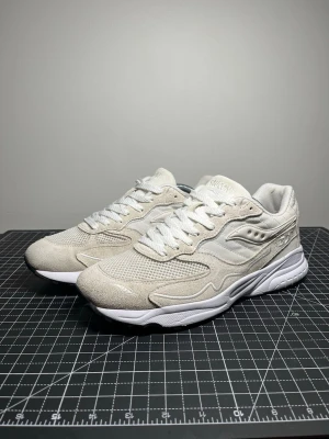 Vita Saucony Shadow 6000 sneakers - Snygga vita Saucony Shadow 6000 sneakers med ovandel i mesh och mocka. Skorna har vita snören, broderad logga på hälen och en chunky vit sula. Perfekta för dig som gillar stilrena och klassiska sneakers med retrovibbar.