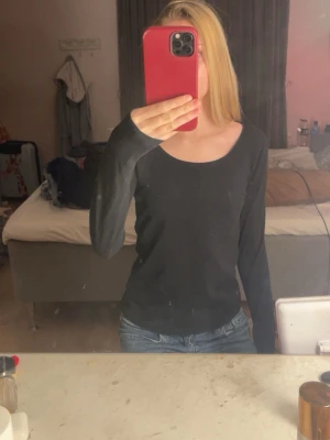 Svart långärmad topp med rund hals - En enkel och stilren svart långärmad topp med rund halsringning. Perfekt basplagg att matcha med jeans eller kjol. Tillverkad i mjukt material som sitter skönt mot kroppen.