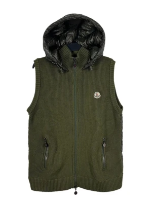 Moncler vest  - Stilren olivgrön dunväst från Moncler med stickad framsida, två dragkedjefickor och avtagbar svart glansig huva. Västen har Moncler-logga på bröstet och hel dragkedja framtill. Perfekt för lager-på-lager och streetstyle.