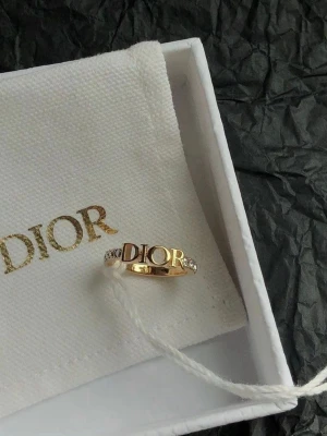 Guldfärgad ring med diamanter  - Snygg guldfärgad ring. Ringen har gnistrande stenar på sidorna som ger extra bling. Perfekt accessoar för dig som gillar lyxiga detaljer och vill sticka ut med en ikonisk design. Ringen själv för 150kr men med box och förpackning blir det 250. Storlek 6 men är ganska flexibel och passar även större och mindre fingrar.