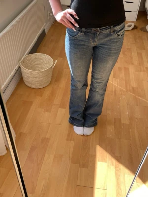 Blå bootcut jeans med låg midja - Blå bootcut jeans med låg midja och klassiska fem fickor. Jeansen har en lätt tvättad look och är tillverkade i denim med lite stretch för skön passform. 