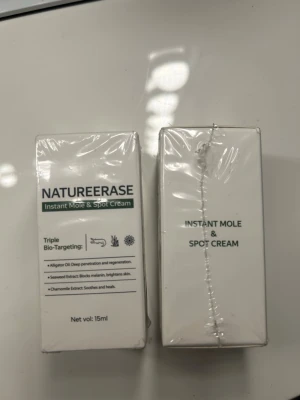 Natureerase Instant Mole & Spot Cream - Natureerase Instant Mole & Spot Cream är en hudkräm på 15 ml som riktar sig mot pigmentfläckar och leverfläckar. Innehåller alligatorolja, sjögräsextrakt och kamomillextrakt för att lugna, ljusa upp och återfukta huden. Kommer i vit förpackning med grön text.