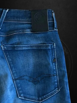 Replay Anbass - Snygga blå slim fit jeans från Replay med klassisk femficksdesign och diskret logga på bakfickan. Jeansen har en lätt tvättad look och smal passform som sitter tajt längs benen. Perfekta för en trendig och avslappnad stil.