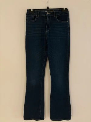 Mörkblå bootcut jeans från Levi's - Mörkblå jeans från Levi's med klassisk femficksdesign och bootcut passform. Jeansen har medelhög midja, dragkedja och knapp framtill samt Levi's ikoniska bakfickor med röd etikett. Perfekta för en avslappnad och trendig look.