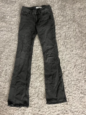 Svarta bootcut jeans/dżinsy - Snygga svarta bootcut jeans från junkyard med klassisk femficksdesign och låg midja. Jeansen har lätt utsvängda ben och är tillverkade i ett stretchigt denimtyg som ger en bekväm passform. Perfekta för en trendig och avslappnad look. Lite slitna där nere som ni ser på de sista bilderna💕