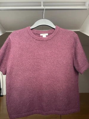 Stickad t-shirt  - Kortärmad stickad t-shirt i en snygg vinröd färg från H&M. Tröjan har rund halsringning och mjuk, lite fluffig struktur. Skulle säga att den är i strl XS/S