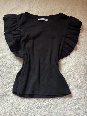 Svart topp med volangärmar från Zara - Svart topp från Zara med volangdetaljer på ärmarna ⭐️storlek M