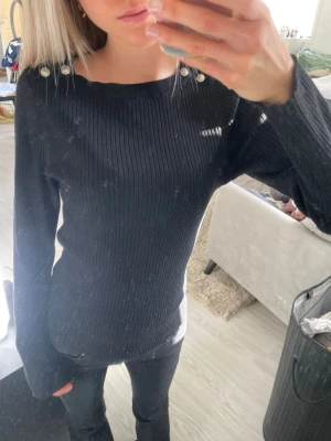 Svart ribbstickad tröja med knappar - Snygg svart ribbstickad tröja med långa ärmar och knappar på axlarna💕