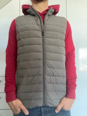 Grå dunväst från Jack & Jones - Grå väst från Jack & Jones. Strl S. Inga defekter. Finns två stora innerfickor (se bild 4). Modellen är 178 cm och väger 77 kg. Hör gärna av dig vid frågor!