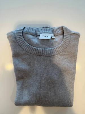 Vila Viril Stickad Tröja XS – Mjuk & Stilren Baströja - Säljer en superfin grå stickad tröja från Vila, modell Viril, i storlek XS. Färgen är den populära “Medium Grey Melange” som passar till allt och fungerar perfekt året runt.  Tröjan har en klassisk passform med rund halsringning samt ribbade detaljer vid ärmslut och nederkant. Den är tillverkad i en mjuk finstickad blandning av viskos och nylon vilket gör den både bekväm och snygg att bära.  ✔ Kanonskick✔ Djur- och rökfritt hem✔ Perfekt basplagg i garderoben