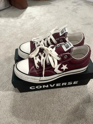 Vinröda Converse One Star sneakers - Säljer ett par vinröda Converse One Star sneakers med vita detaljer och klassisk vit sula. Skorna har lågt skaft, vita skosnören och den ikoniska stjärnan på sidan. Ovandelen är i canvas och sulan i gummi. Storlek 37,5. Perfekta för en avslappnad streetstil. Använt väääldigt få gånger, kanske 3 gånger😅❤️