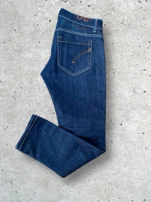 Mörkblå slim fit jeans från dondup - Snygga mörkblå slim fit jeans från dondup med klassisk femficksdesign och kontrastsömmar. Jeansen har en rak passform och är tillverkade i ett mjukt denimtyg som ger en bekväm känsla. Perfekta för dig som gillar en stilren och enkel look.
