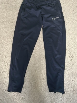 Svarta Nike mjukisbyxor med logga - Svarta mjukisbyxor från Nike med vit broderad logga på ena benet. 