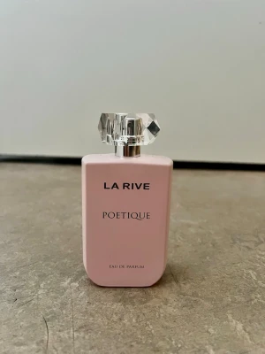 La Rive Poétique Eau de Parfum - Snygg parfymflaska i ljusrosa från normal med namnet La rive, Poétique. Flaskan är använd 3 gånger och är nöstan helt full. Flaskan har en elegant, fyrkantig form och ett genomskinligt, kristalliknande lock som ger en lyxig känsla. Perfekt för dig som gillar stilrena och feminina dofter.