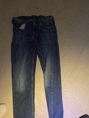 Mörkblå raka jeans - Snygga mörkblå jeans med rak passform och klassiska fem fickor. Jeansen har en tidlös look med lätt slitning och normal midja. Perfekta för en avslappnad stil och passar till det mesta. Materialet är denim i bomull.