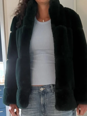 Svart pälsjacka med krage - Mysig svart pälsjacka med bred krage och rak passform. Jackan är tillverkad i mjukt fuskpälsmaterial och har en stilren look som passar perfekt till kalla vinterdagar. Enkel att matcha med olika outfits för en trendig vibe.
