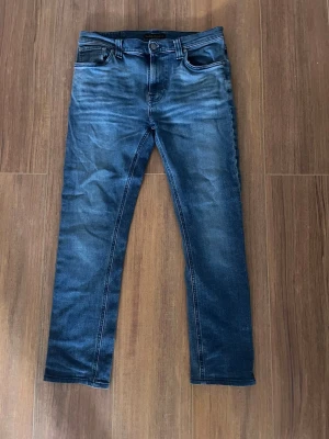 Mörkblå slim fit jeans - Snygga mörkblå slim fit jeans med klassisk femficksdesign och lätt slitning framtill. Jeansen har normal midja, smala ben och är tillverkade i stretchigt denimtyg för extra komfort. Perfekta för en trendig och avslappnad look.